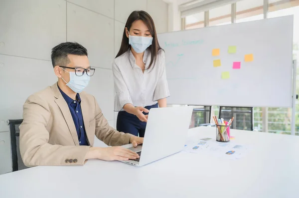 在现代办公室的会议室里 亚洲男性和女性企业家戴着面罩在笔记本电脑上讨论商业项目 — 图库照片