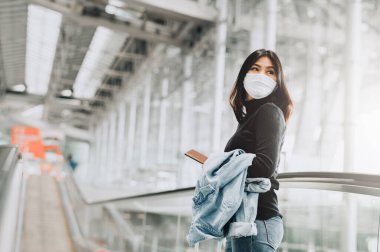 Coronavirus ya da covid-19 salgını sırasında havaalanı terminalinde pasaportlu Asyalı kadın turist. Havaalanında yeni normal seyahat