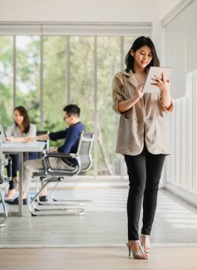 Toplantı odasında meslektaşı ile birlikte dijital tablet kullanan mutlu Asyalı kadın. İş başarısı veya başarı kavramı