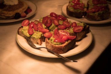 Avokado guacamole tost plakaları bir mutfak tezgahı üzerinde kiraz patates ile