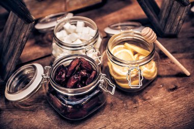 Kurutulmuş tarihleri, cuted limon, şeker cam saklama kapları ve bal sopa ahşap vintage sehpa üzerinde çay için