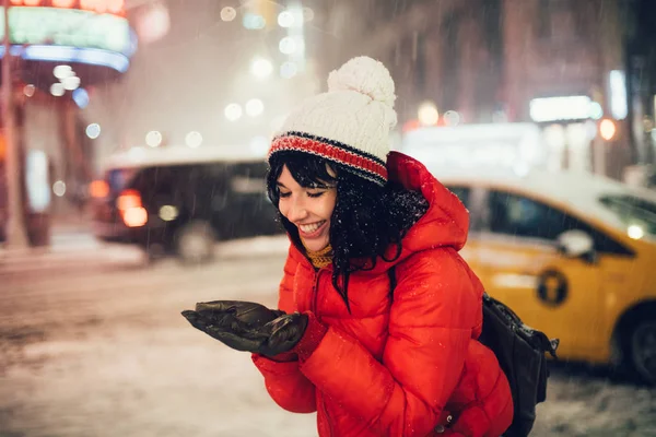 幸せな椰子の木に雪の結晶をキャッチの女性を興奮して夜の街に最初の雪を楽しむ — ストック写真