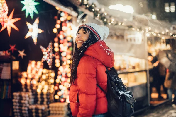 クリスマス市の雪嵐の中にフェアでプレゼントを探して美しい幸せな女 — ストック写真