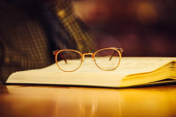 ライブラリのテーブルの上に置いてある本に金高級メガネ — ストック写真