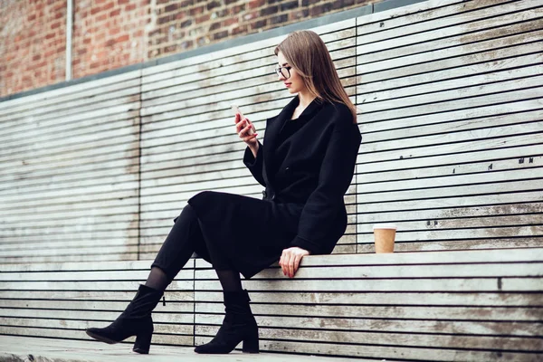 アウトドアやテキスト メッセージをコーヒーを飲みながら彼女の電話に座って幸せ笑顔の女性 — ストック写真