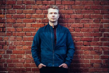 Sıradan kıyafetler giyen turuncu tuğla duvar yakınında poz yakın Blonde yakışıklı adam