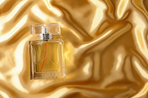 香水瓶在金丝折叠式面料背景上 黑色金液玻璃瓶 色香味化妆品 — 图库照片