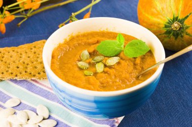Bir kasede kabak çorbası otlar, kabak tohumları ve çavdar ekmeğiyle servis edilir. Vejetaryen çorbası. Mavi arkaplan.