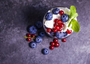 Üzümlü yoğurt ve koyu arkaplanda yabanmersini.