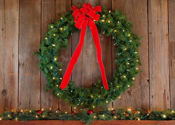 圣诞花环挂在雪松墙上 上面有红带的圣诞花环 图库图片