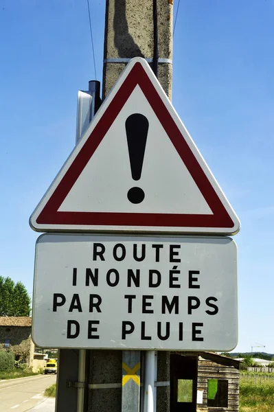 Road sign indicating flood hazard in rainy weather — Stock Photo, Image