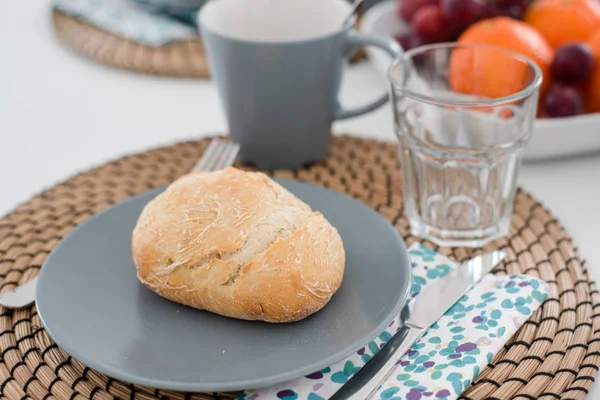 Plate with fresh crusty bread and glass of juice on grey plate — Stock Photo, Image