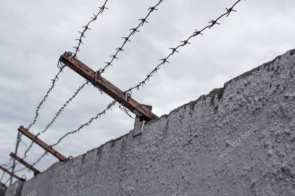 Concrete fence with barbed wire. Freedom, jail, prison, human rights concept.