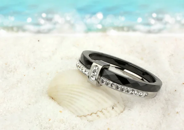 Anel de jóias com diamantes na praia de areia como fundo — Fotografia de Stock