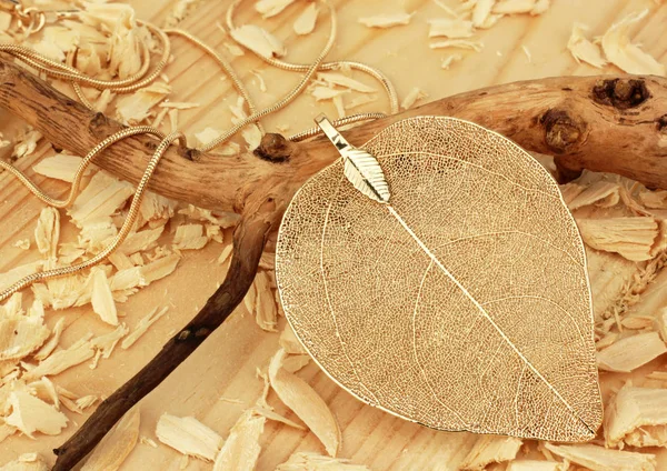 Smycken hänge, form av löv, på trä sågspån bakgrund — Stockfoto