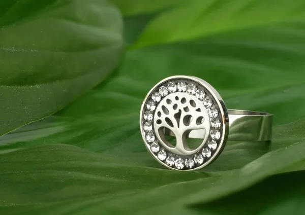 Jewelry ring with diamonds, shape of tree, on green leafs as bac — Stock Photo, Image