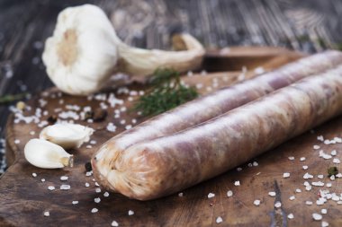 Sarımsak ve maydanoz kesme tahtası üzerinde çiğ sosis