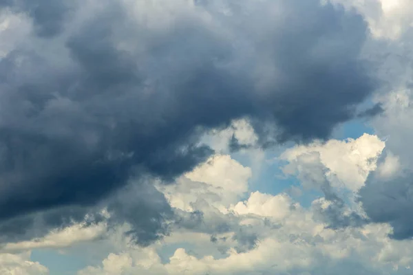 heavy dark rain clouds with storm and blue sky with puffy clouds in background