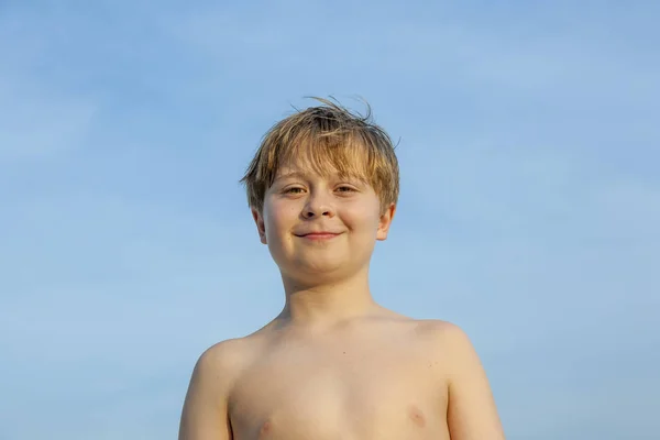 在蓝天的背景下 在海滩上快乐地微笑着的小男孩 — 图库照片