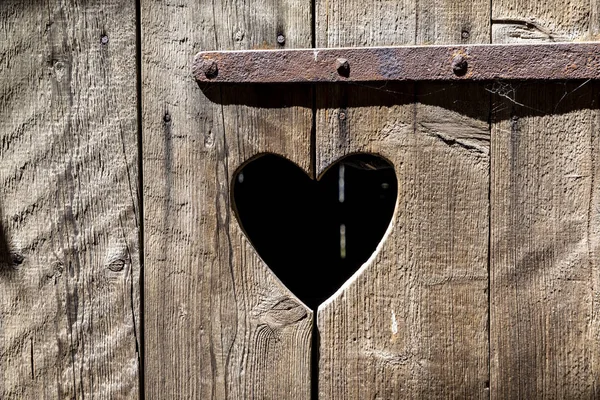 Forma di cuore a una porta vecchia di legno di un gabinetto — Foto Stock