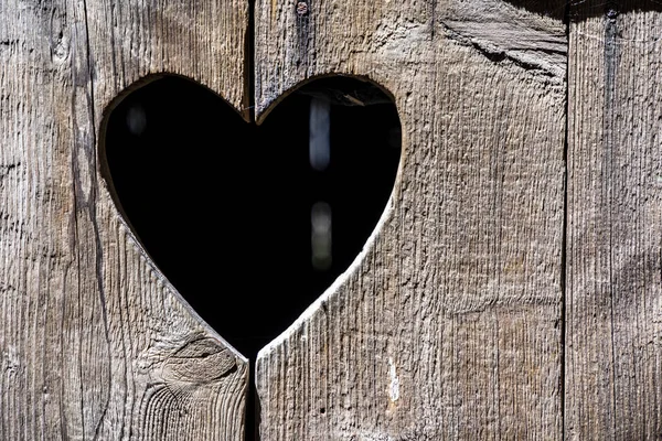 Forma di cuore a una porta vecchia di legno di un gabinetto — Foto Stock