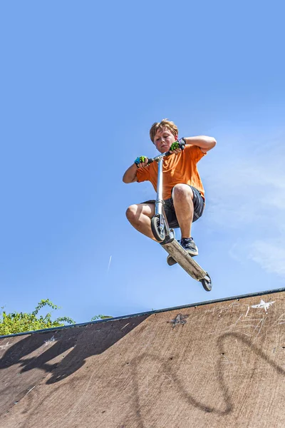 Хлопчик любить штовхати скутер, катаючись на ковзанах парку — стокове фото