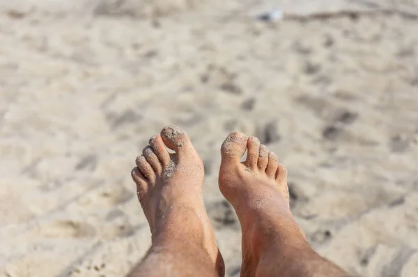 Genç adamın ayakları kumsalda dinleniyor. — Stok fotoğraf