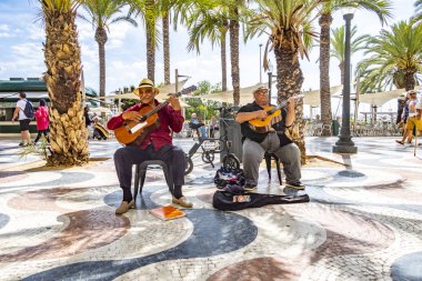 Alicantes parkındaki müzisyenler el sallayarak ünlü gezinti yapıyorlar.