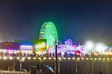 İnsanlar geceleri Santa Monica rıhtımındaki okyanus parkının tadını çıkarıyor.