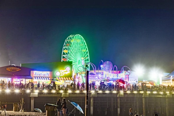 People enjoy the ocean park at Santa Monica pier by night — Stock Photo, Image