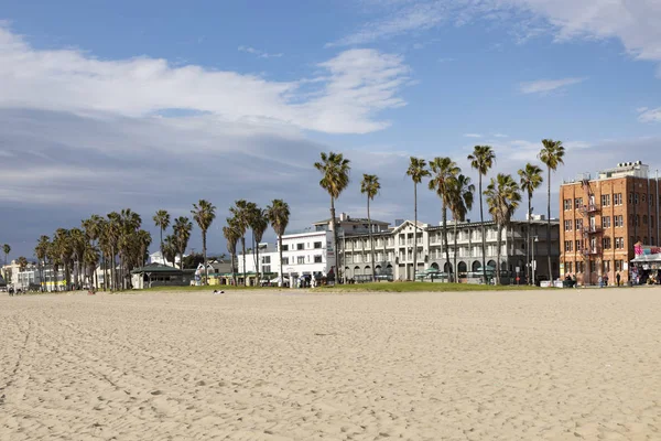 People enjoy scenic beach promenade with palms and colorful hous — Stock Photo, Image