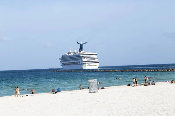 People enjoying the beach next to a cruise ship leaving Miami ha — Stock Photo, Image