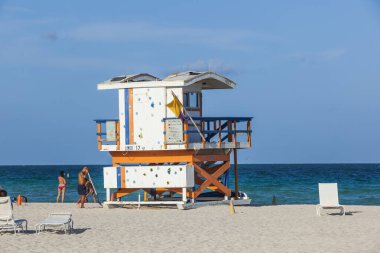 insanlar bir cankurtaran kulesinin yanında kumsalın tadını çıkar.