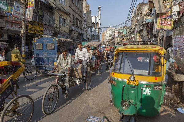 Hombre lleva carga y la gente con su rickshaw en el viejo Delhi —  Fotos de Stock