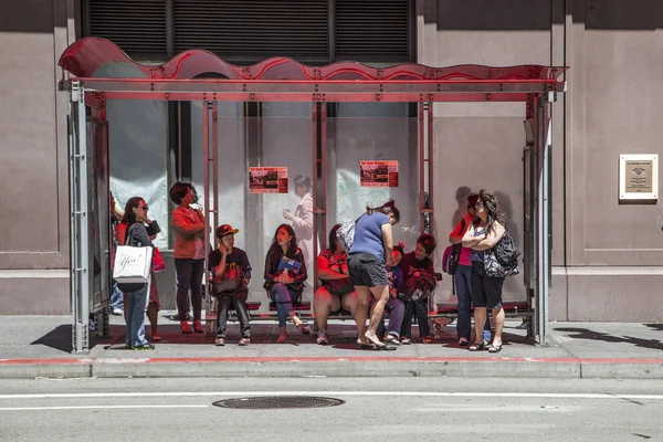 Persone aspettano in uno stand ad una fermata del bus per il prossimo autobus a mezzogiorno h — Foto Stock