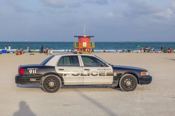 Polis arabasında bir polis memuru öğleden sonra güney plajı boyunca araba sürüyor. — Stok fotoğraf