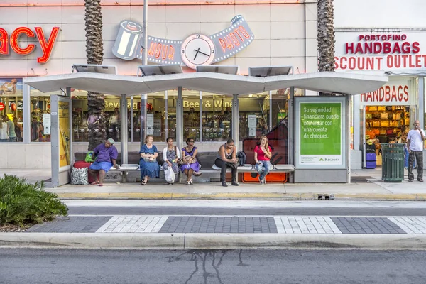 Folk väntar vid en busshållplats framför en apotek butik. Offentlig upphandling — Stockfoto