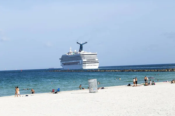 Люди наслаждаются пляжем рядом с круизным лайнером, выходящим из Майами — стоковое фото