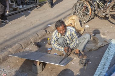 man with saw cuts a rigips plate at the street in old Delhi, Cha