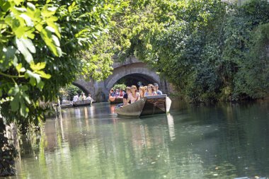 İnsanlar Colmar 'da yeşil bir kanalda tekne gezisinin keyfini çıkarıyorlar.