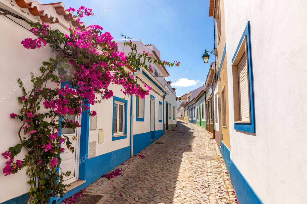 small cobble stone road in the former fisher village of Ferragudo at the Algarve area with blooming bougainvillea