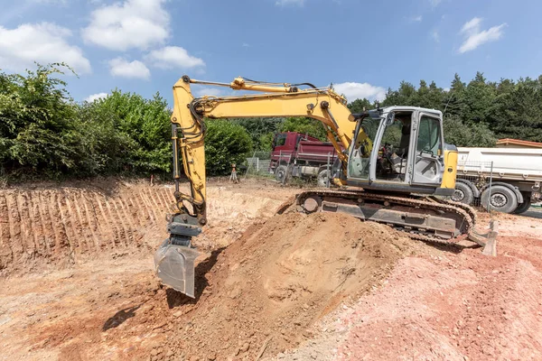 large digger digs a hole for the cellar of a family house