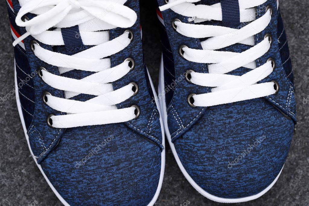 Pair of blue sneakers, closeup of white shoelaces