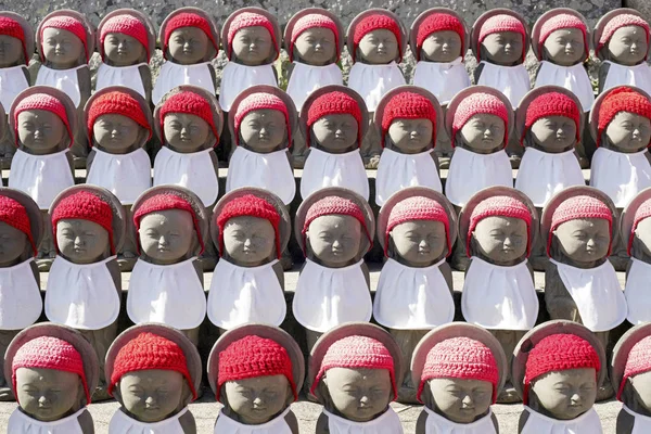 一排佛教的米祖科吉佐雕像与白色围裙 红色帽子 — 图库照片