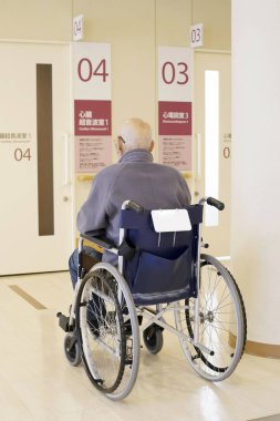 Hastanede tekerlekli sandalye üzerinde oturan üst düzey veya yaşlı adam arkadan görünüm 