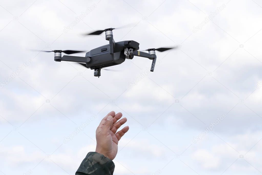 Hand catching drone aircraft in sky background, camera operator concept