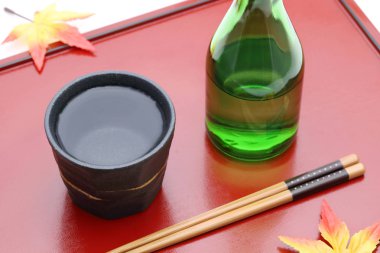 Japon Shochu şişesi ve seramik kase tahta tepside, beyaz arka planda.   