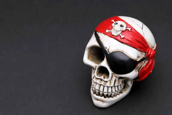 Pirate skull with red head kerchief on dark background