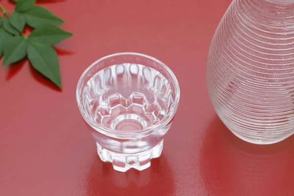 透明玻璃杯中的日本清酒和红色背景上的罐子 — 图库照片