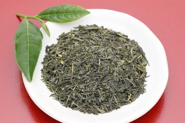干茶叶与红色背景的绿茶叶 — 图库照片